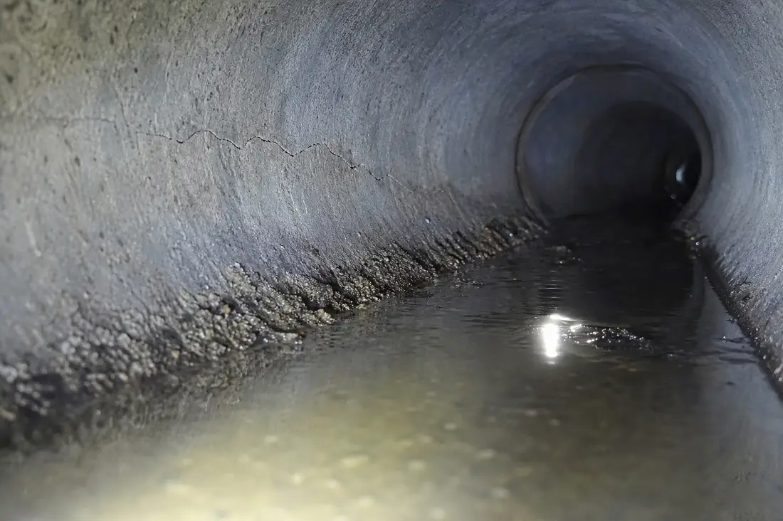 Innenansicht eines Abwasserrohrs mit feinem Riss und stehendem Wasser als Hinweis auf falsches Gefälle