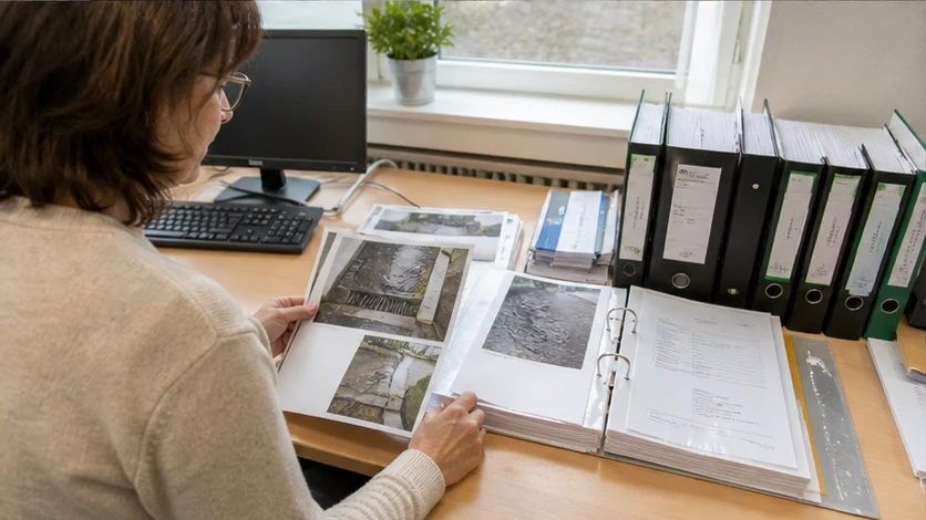 Verwalterin ordnet Fotos, Notizen und einen Rapport für eine Abklärungsanfrage